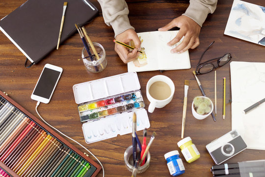 Cropped image of male illustrator making painting at desk in creative office
