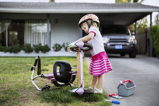 Side view of a girl repairing bicycle in lawn