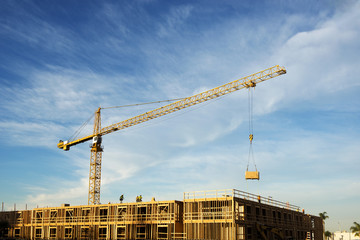 Crane at construction site against cloudy sky