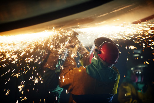 Rear view of worker welding airplane wing at industry