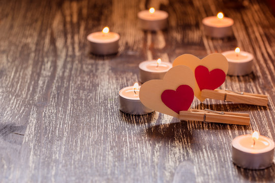 Paper hearts on clothespins  and burning candles on  wooden table