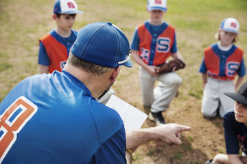 Coach pointing while discussing with baseball team on field