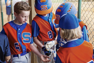 Baseball player giving bubble gums to friends outdoors