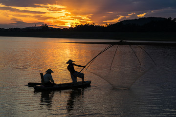 Dong Mo lake with a couple of fishers catching fish by net trap in beautiful sunset period in Son Tay town, Hanoi, Vietnam