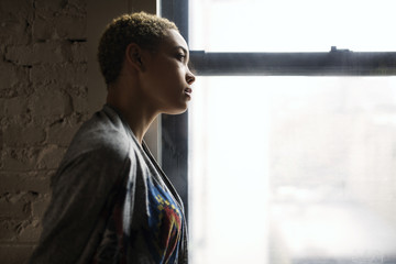 Side view of thoughtful woman standing by window at home