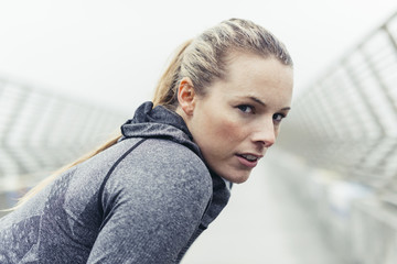 Portrait of tired female athlete on bridge