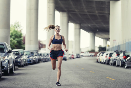 Female Athlete Running On Street Under Bridge