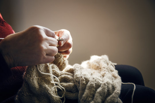 Midsection of senior woman knitting at home