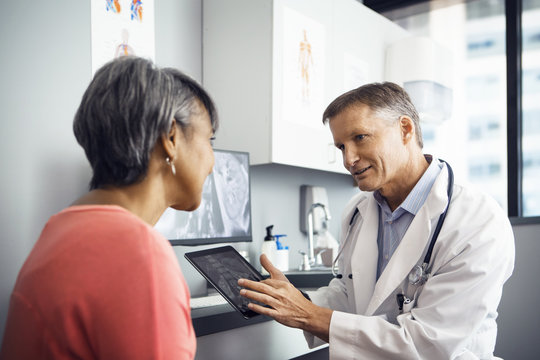 Male doctor explaining x-ray on tablet computer to patient in clinic