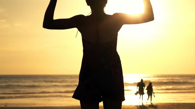 Happy woman jumping on the beach  during sunset, super slow motion
