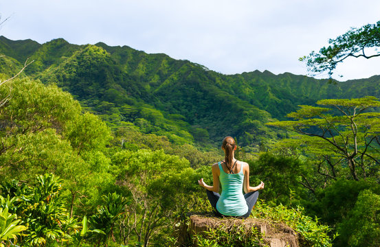 Woman meditating in a green nature setting. 