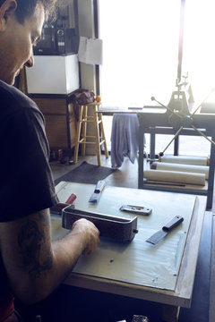 Cropped image of male lithograph worker using paint roller at workshop
