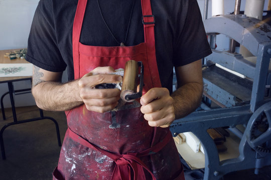 Midsection of worker cleaning paint roller at workshop