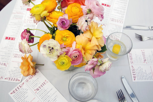 High angle view of flower vase with menus and water glasses on restaurant table