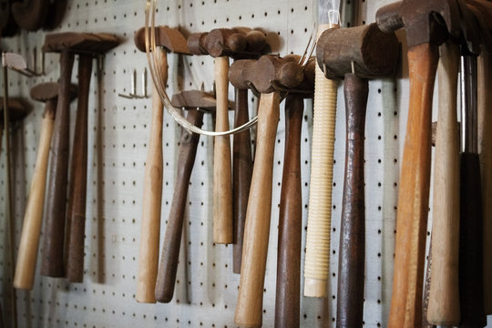 Close-up of hammers hanging on wall in workshop