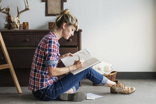 Female artist drawing in book while sitting at home