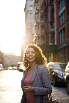 Happy businesswoman looking away while standing on city street
