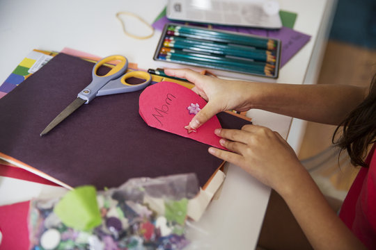Cropped image of girl making greeting card for mother on table