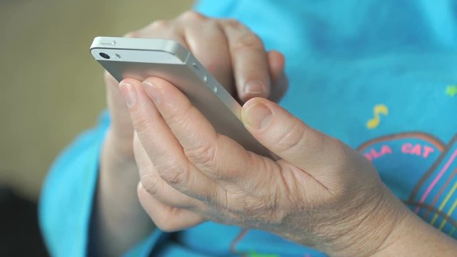 Woman's hand holding the silver smartphone. Close up