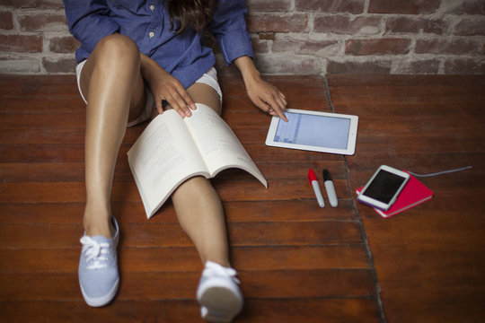 Overhead View Of Woman Using Tablet Computer While Studying On Wooden Floor