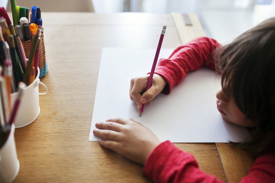 Boy Drawing On Paper At Desk