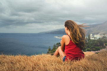 Junge hübsche sportliche Frau sitzt am Meer und schaut auf den Horizont