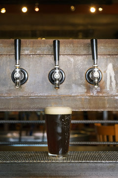 Beer glass under beer tap in a bar