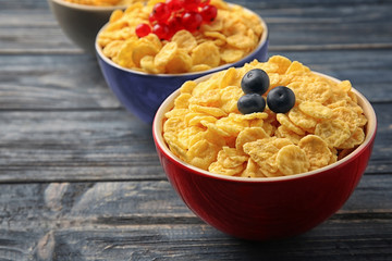Bowls with cornflakes and berries on grey wooden background, closeup