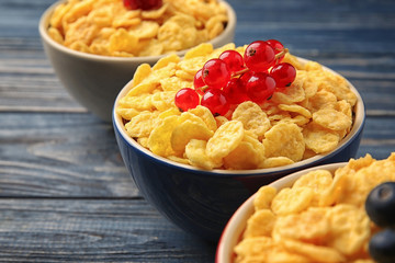 Bowls with cornflakes and berries on grey wooden background, closeup