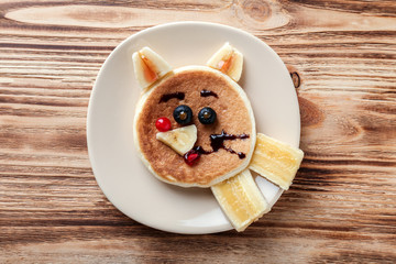 Plate with creative homemade pancake on wooden table