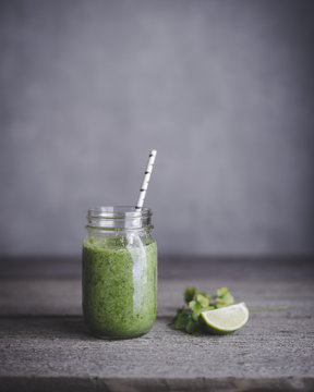 Green smoothie in mason jar with lime on table