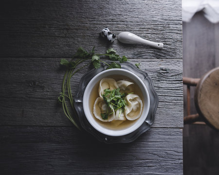 Overhead view of Chinese dumpling soup served in bowl on table