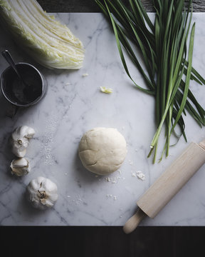 Overhead view of vegetables with dough on kitchen counter