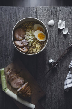 Overhead view of char sui pork and ramen noodles with egg on wooden table