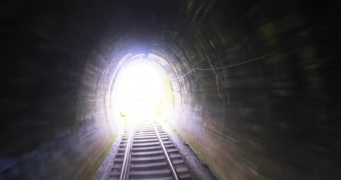 Abstract video of fast moving camera through old railway tunnel toward bright light