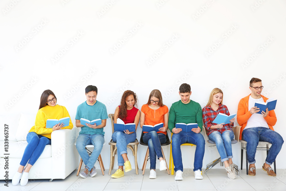 Poster Group of people reading books while sitting near light wall