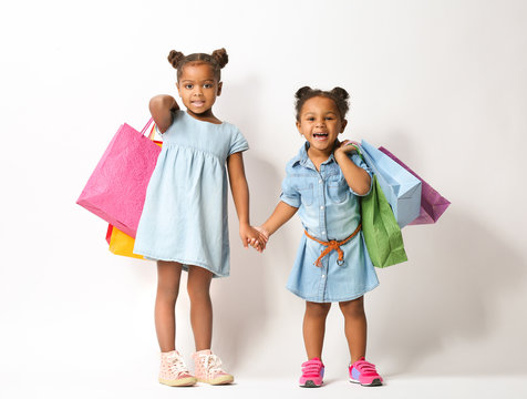 Two cute African girls with shopping bags on white background