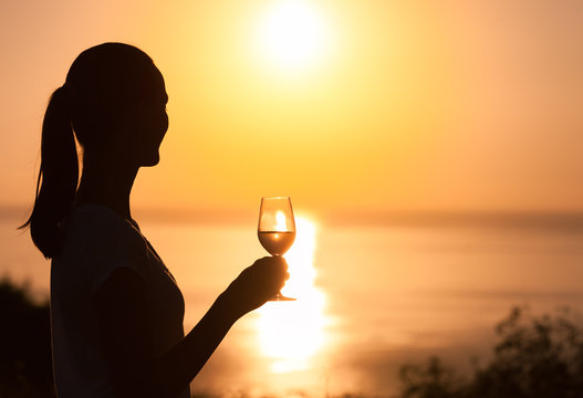 Girl drinking a glass of wine overlooking a beautiful sunset. 