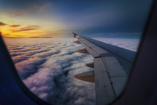 Scenic view of clouds seen through airplane window during sunset