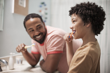 Happy father and son brushing teeth in bathroom