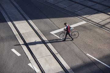 High angle view of man walking with bicycle on road