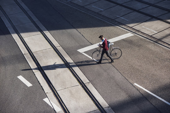 High angle view of man walking with bicycle on road