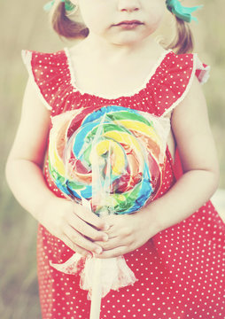 Midsection of girl holding multi colored candy outdoors