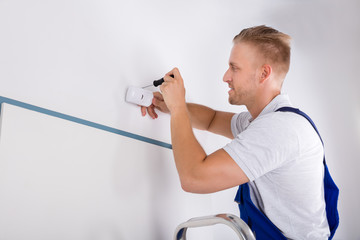 Man Installing Motion Detector For Security System
