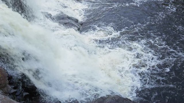 Peaceful nature scene of a waterfall in the woods. Pan shot above falls, filmed at Gooseberry Falls in Northern Minnesota, USA. With audio.