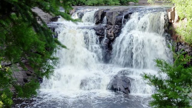 Peaceful nature scene of a waterfall in the woods. Filmed at Gooseberry Falls in Northern Minnesota, USA. With audio.