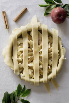 Overhead view of apple pie with apple and cinnamons on table