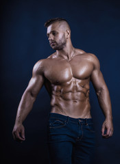 Obraz na płótnie Canvas Handsome muscular bodybuilder posing over dark background