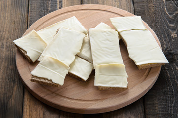 slices of cheese on bread toasts wooden background