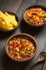 Vegetarian chili dish made with kidney bean, carrot, zucchini, bell pepper, sweet corn, tomato, onion, garlic, photographed with natural light (Selective Focus, Focus in the middle of the first dish)